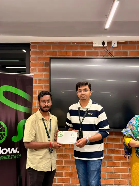 Two people holding a certificate in front of a screen