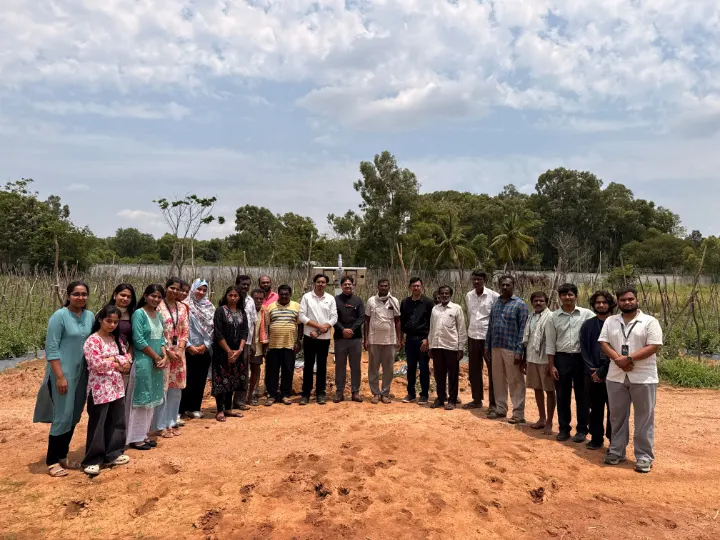 A large group standing in a line on red soil before a field