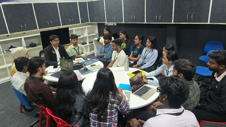 People seated at round tables with laptops, listening