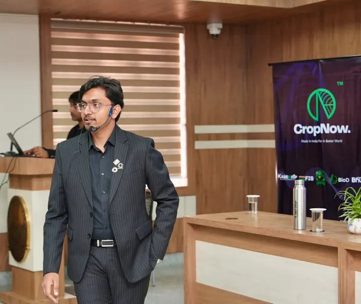 Mohammed Kabeer standing by a podium and a CropNow banner