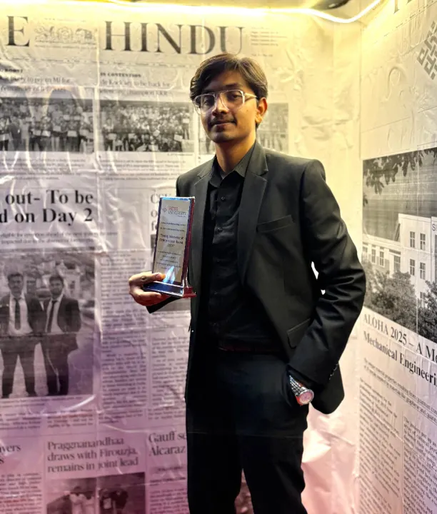Mohammed Kabeer holding a trophy before a wall of newspaper pages