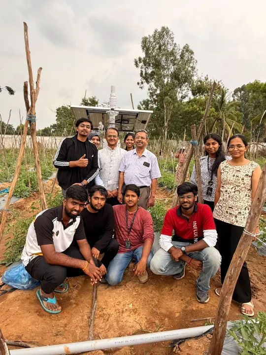 The team and farmers crouching and standing together in a field