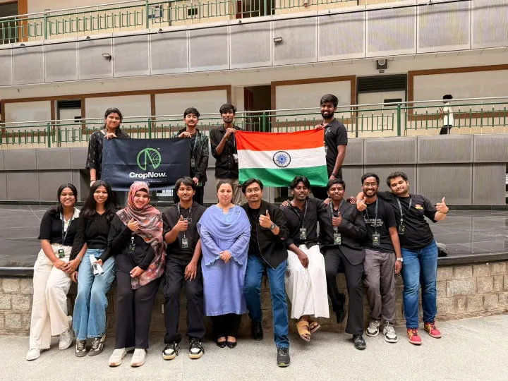 The team seated and standing with the Indian flag and a CropNow banner