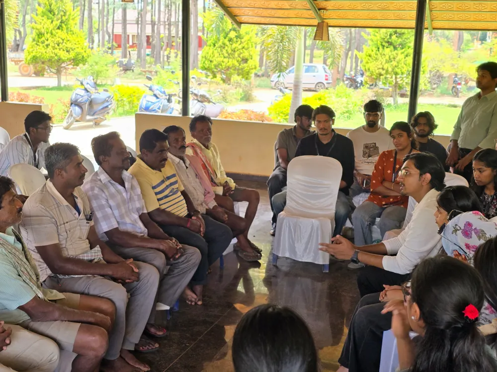 Farmers seated in a circle under an open shelter